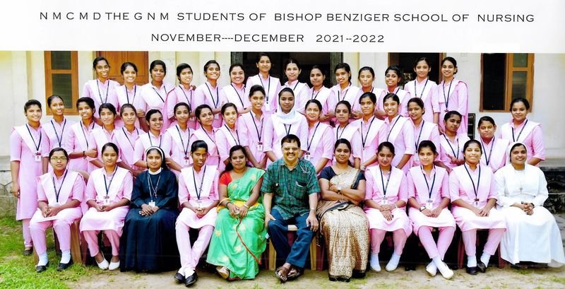 Group photo of GNM nursing students in pink uniforms with Dr. Nicholas Christy seated in the centre
