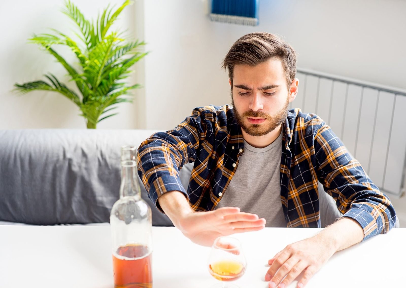 A young man holding up his hand to refuse a glass of alcohol